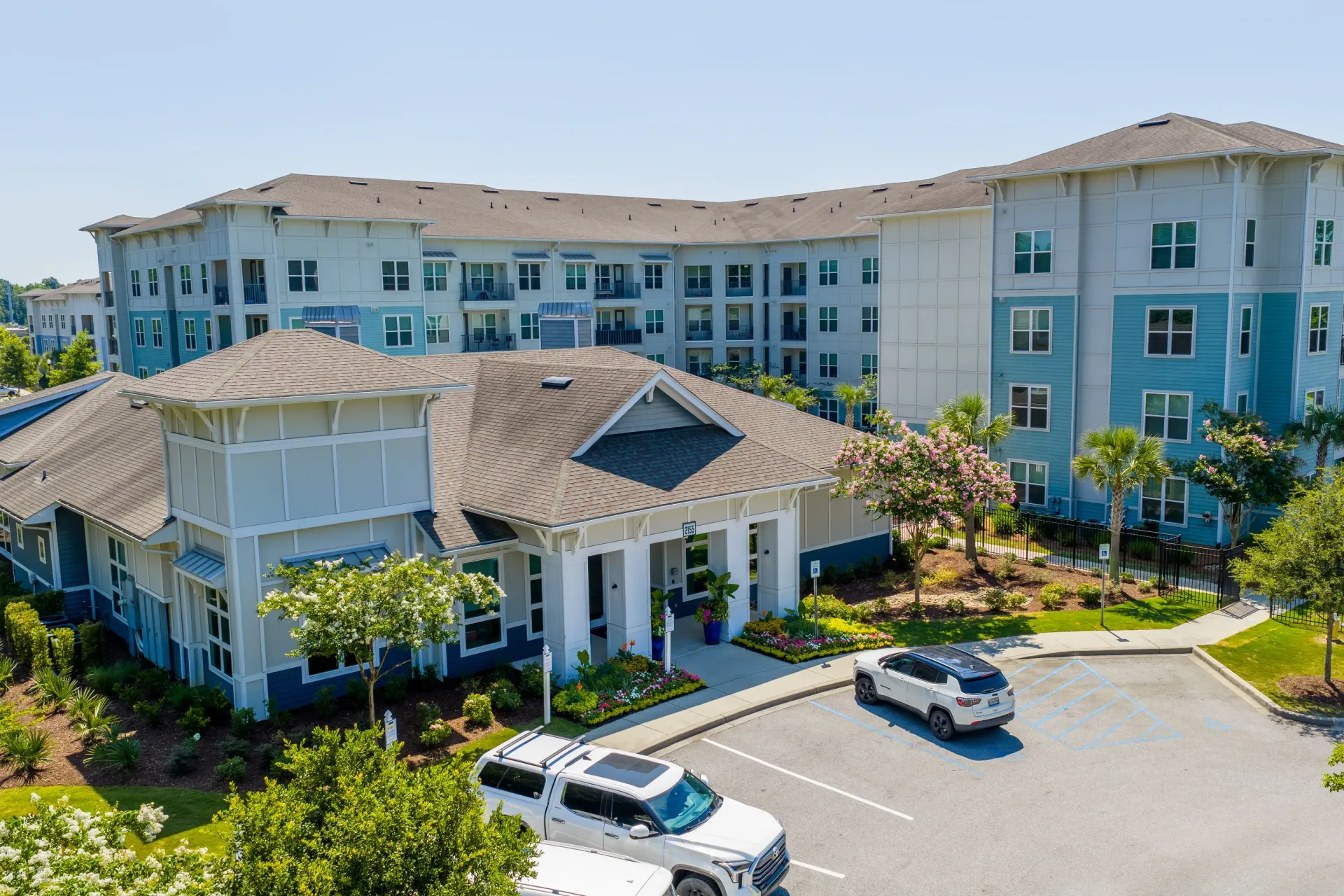 Exterior view of a modern apartment building complex with a central clubhouse and ample parking at Atlantic on the Boulevard in North Charleston, SC.