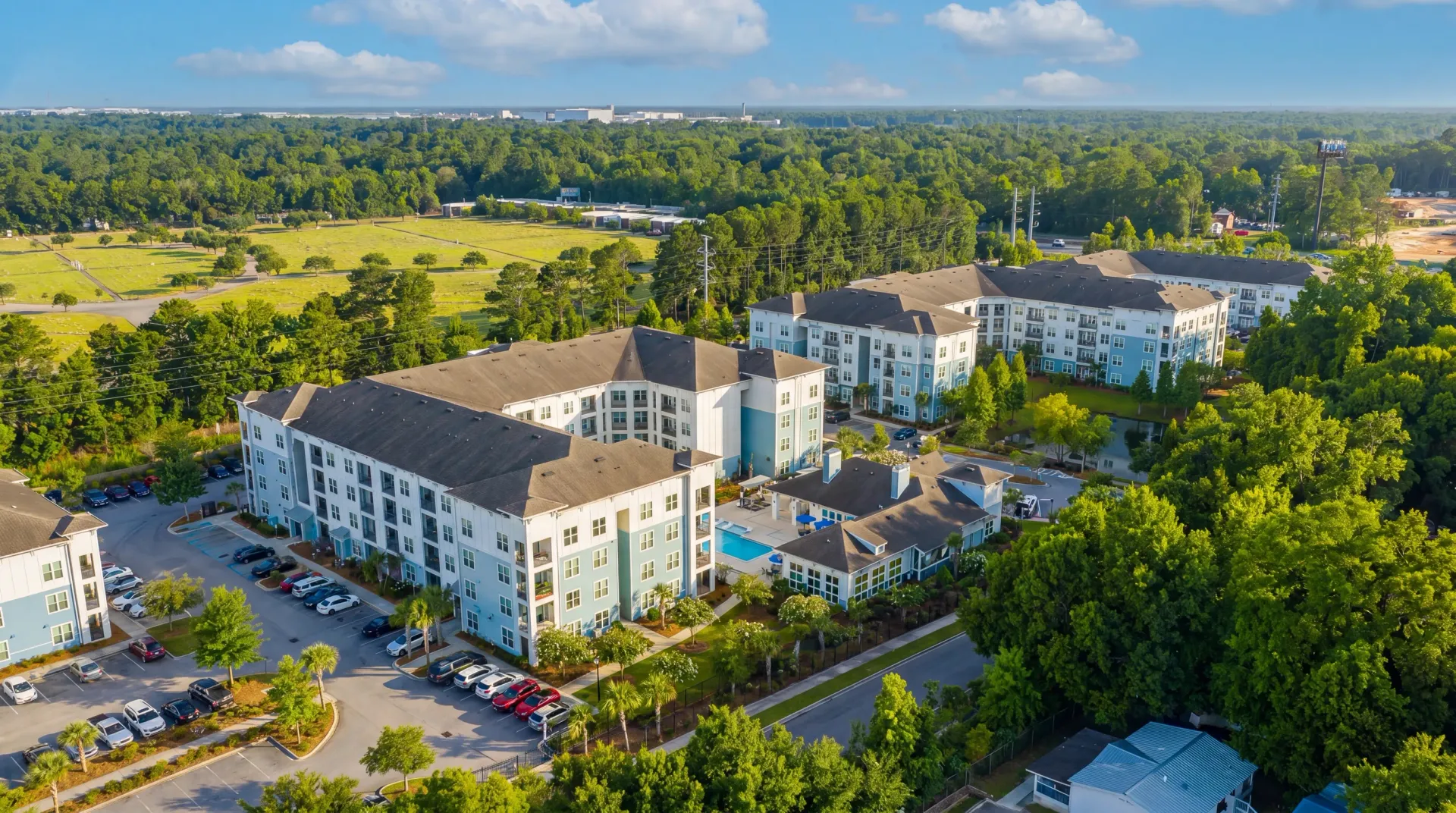 Aerial view of apartment buildings with a pool and surrounding greenery at Atlantic on the Boulevard in North Charleston, SC.