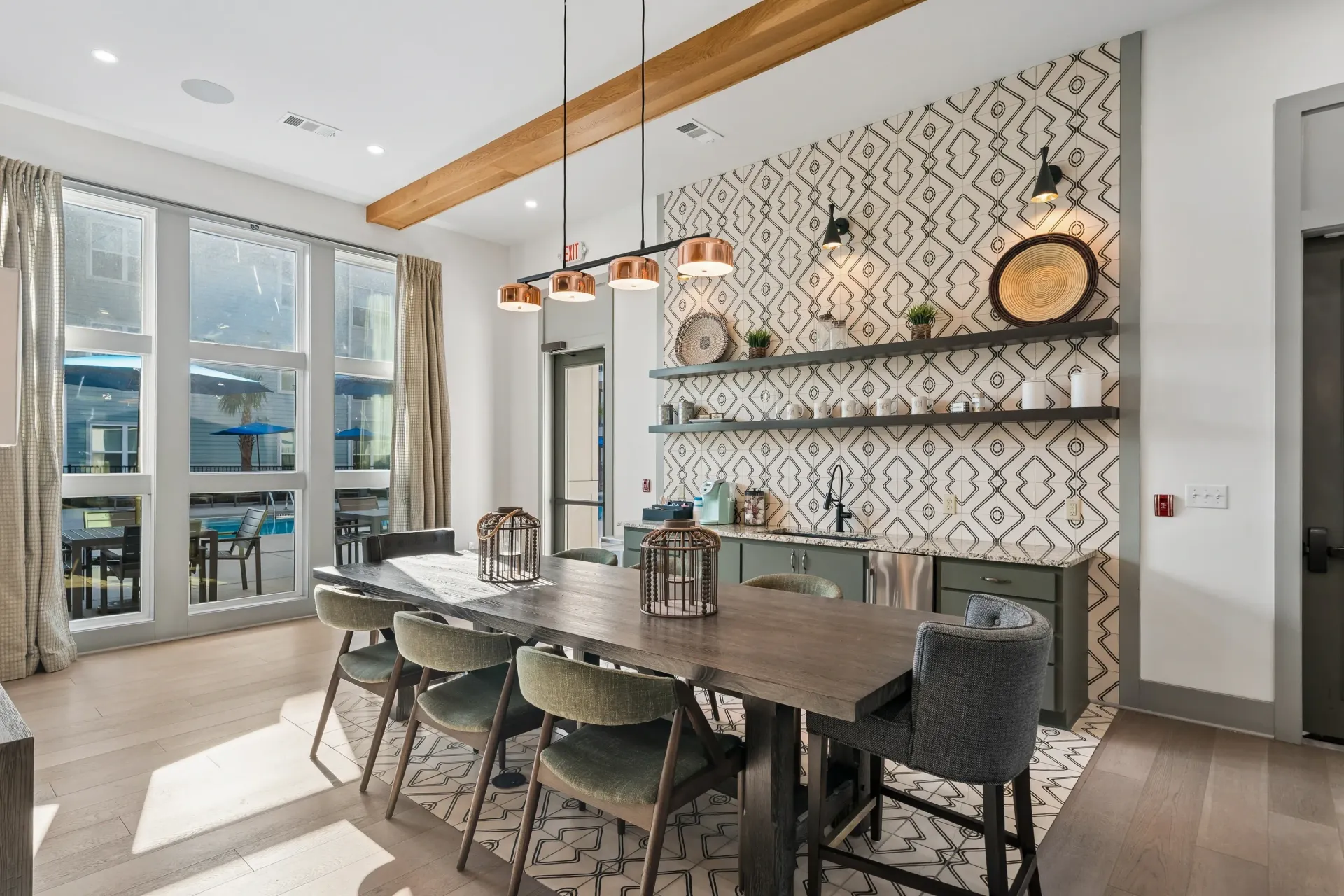 Community dining area with large wooden table and chairs, view of pool through large windowsat Atlantic on the Boulevard in North Charleston, SC.