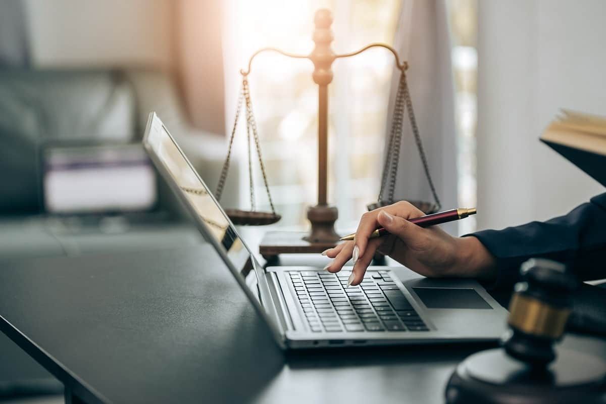A lawyer typing on a laptop next to pair of judicial scales near Lexington, Kentucky (KY)