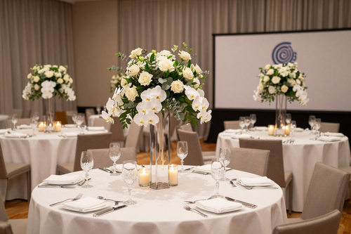 Round banquet table with white floral centerpieces and candles in a softly lit event room