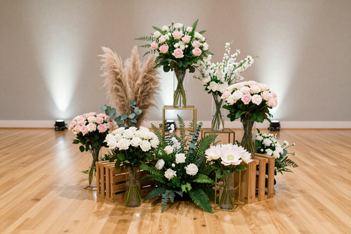 Floral arrangement with pink and white flowers, greenery, and pampas grass on a wood floor