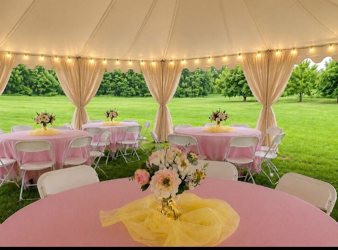 Pink decorated tables under a tent with draped curtains overlooking a green lawn
