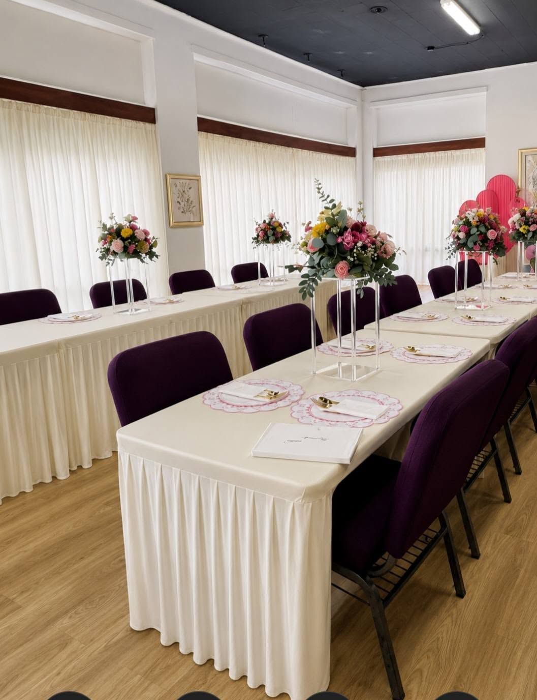Decorated banquet room with long white tables, purple chairs, and floral centerpieces