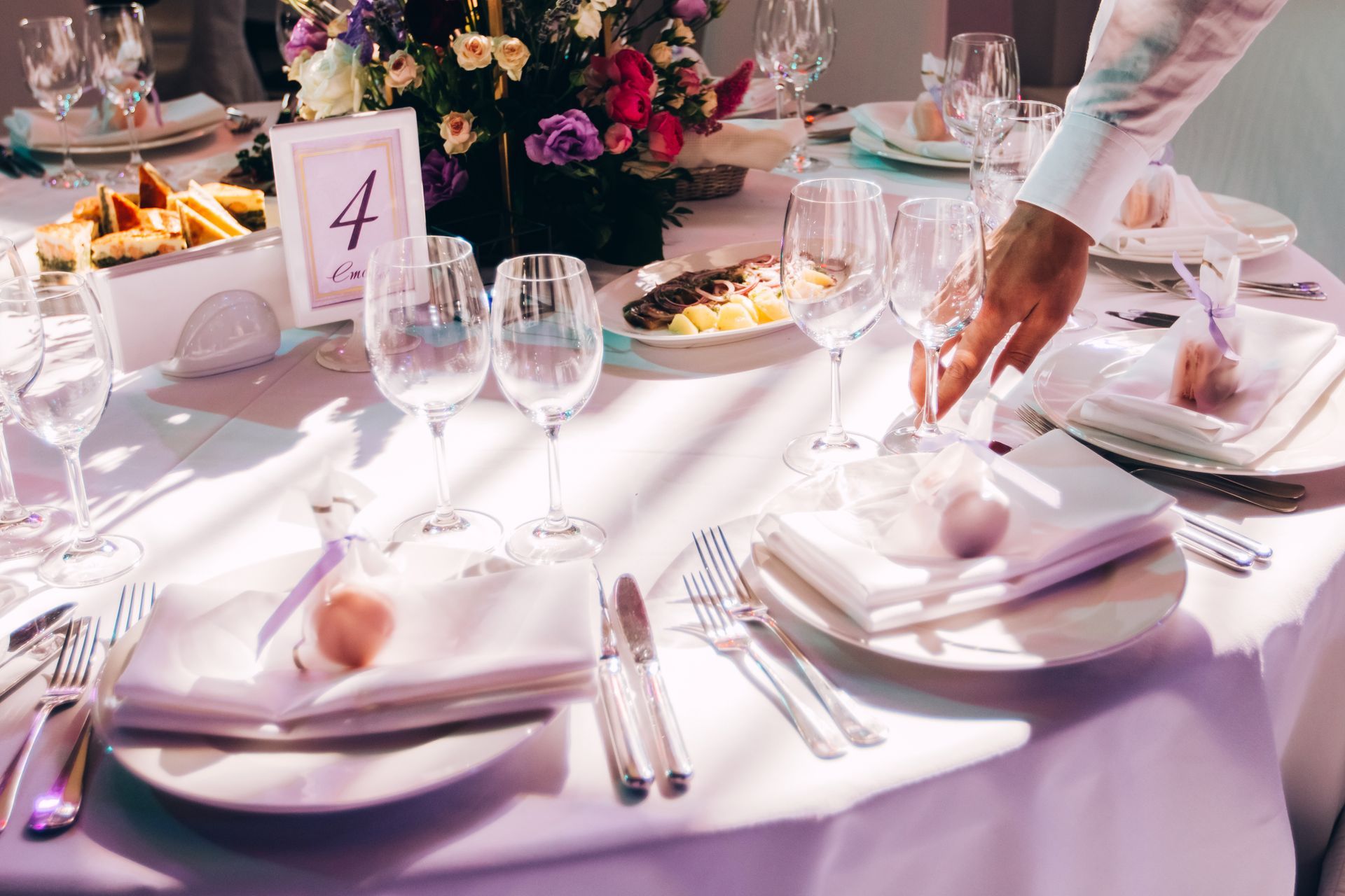 Elegant banquet table with pink linens, folded napkins, wine glasses, floral centerpiece, and table number 4
