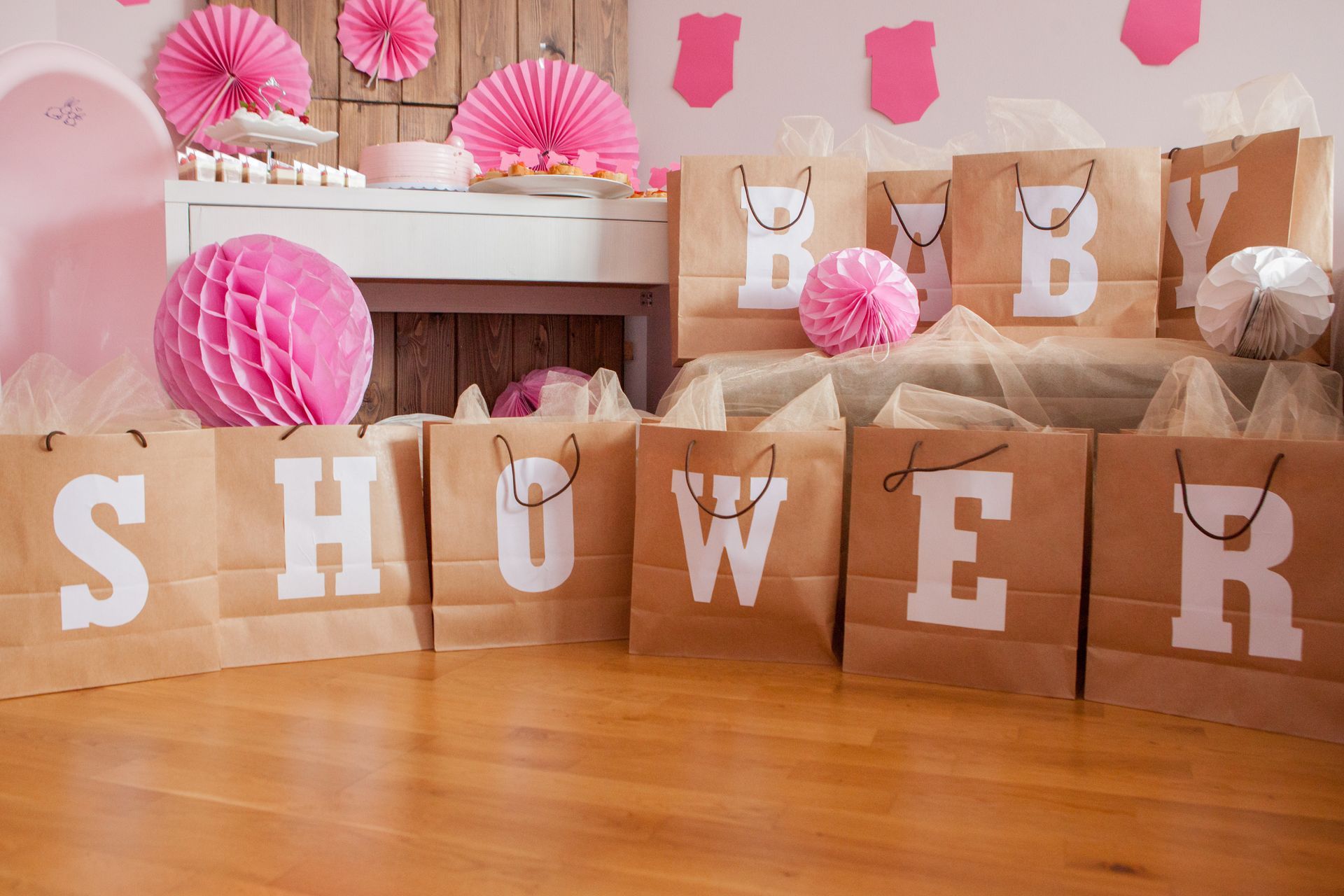 Baby shower decorations with paper bags spelling “SHOWER” and pink accents on a table