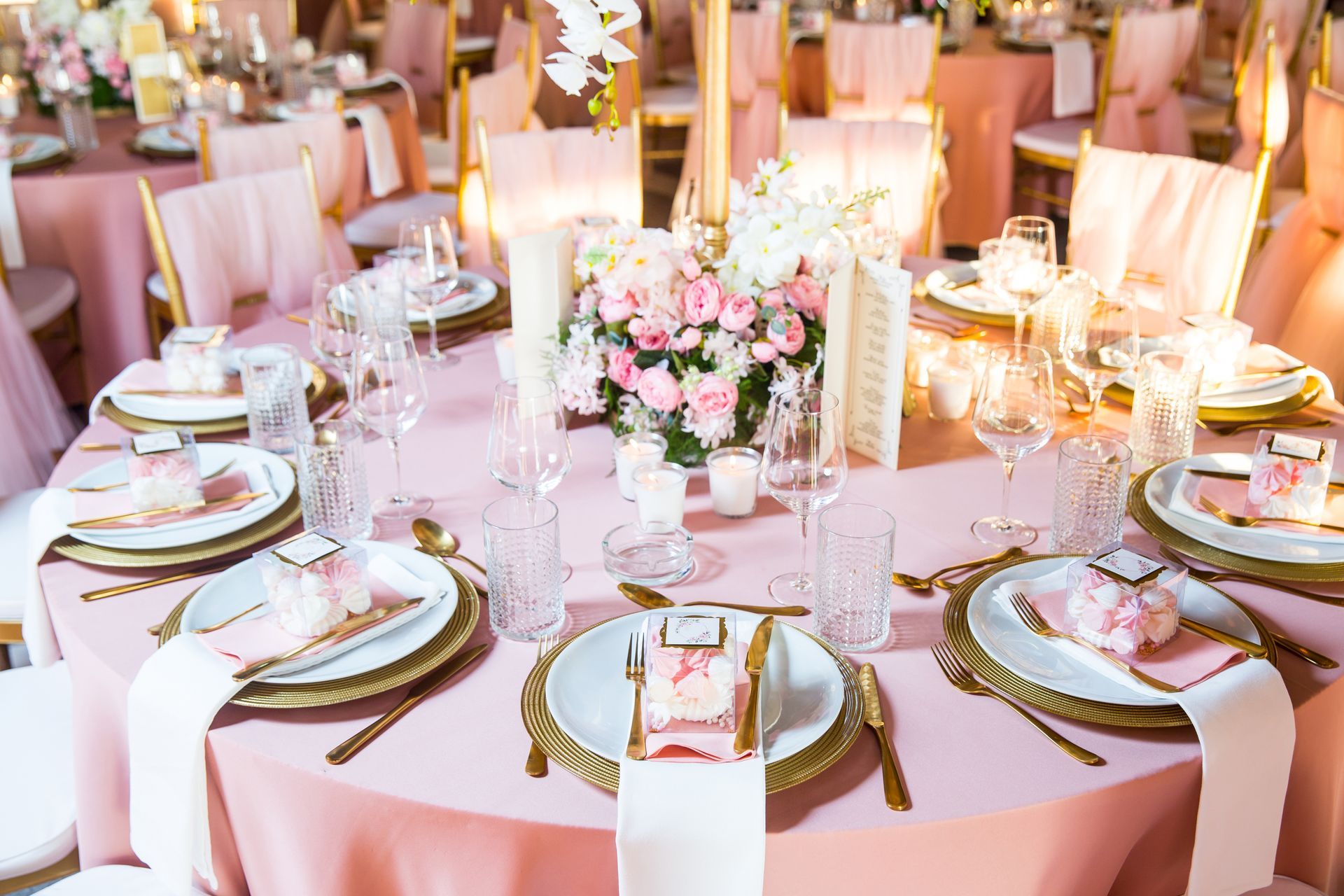 Elegant banquet table with pink floral centerpiece, gold accents, and place settings at a formal event
