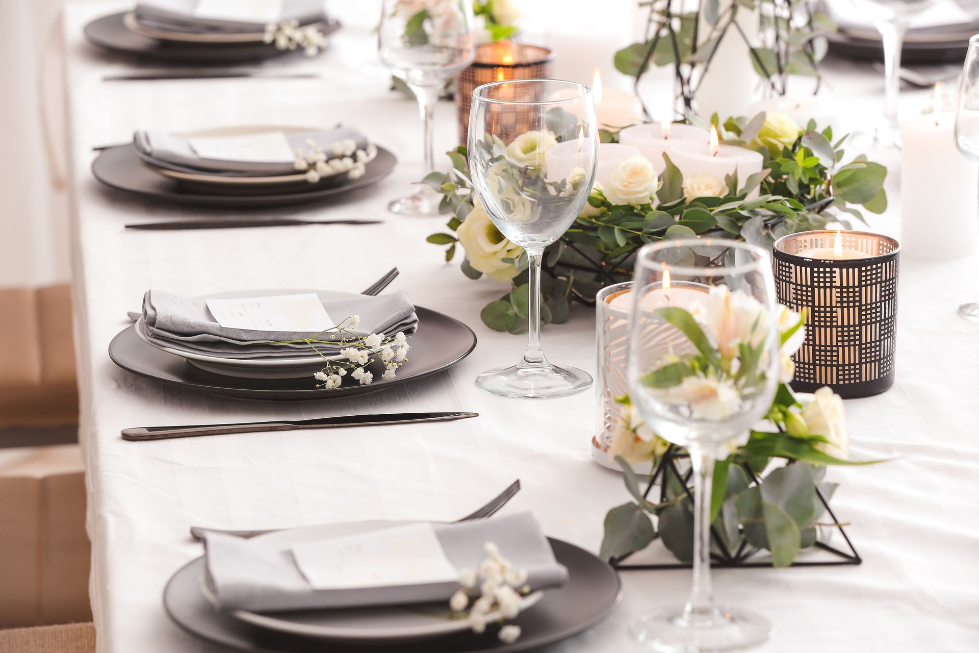 Elegantly set dining table with white tablecloth, plates, glasses, and floral centerpieces