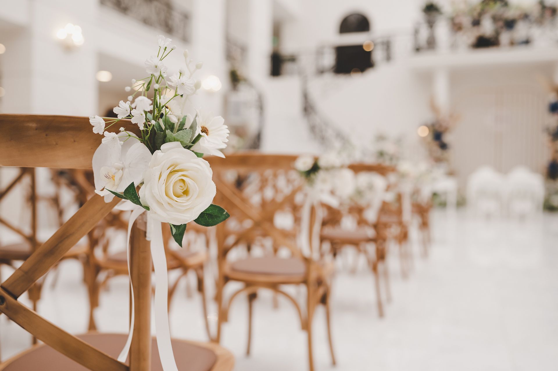 White floral wedding aisle with wooden chairs and soft blurred background