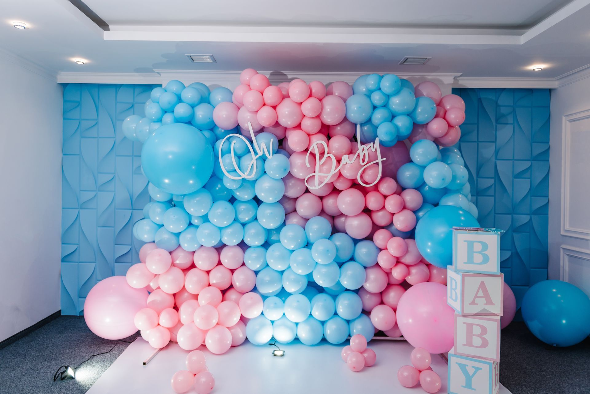 Pastel blue and pink balloon backdrop with “BABY” blocks, for a baby shower or gender reveal