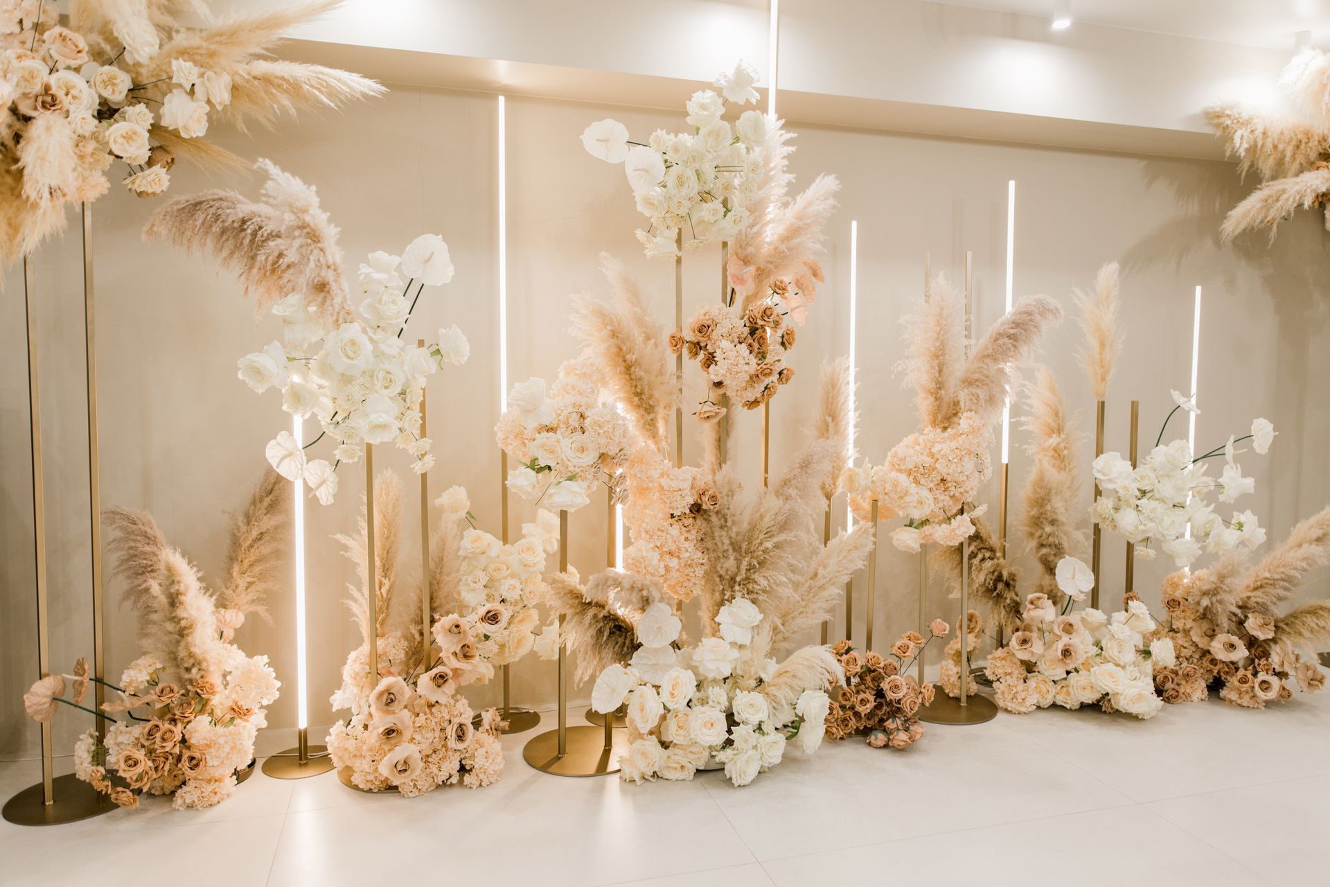 Elegant cream and white floral stage backdrop with tall candles and dried arrangements