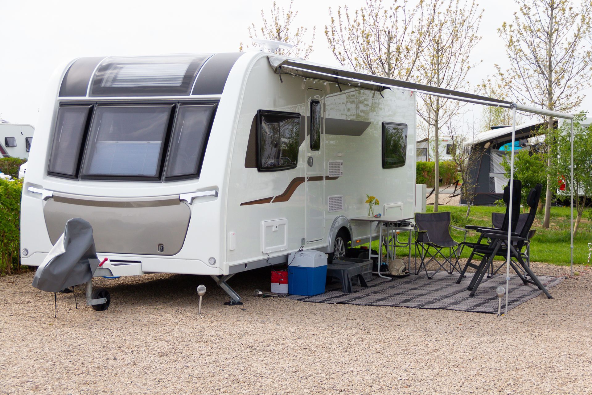 Touring caravan set up with awning, outdoor chairs, and leisure gear on a campsite.
