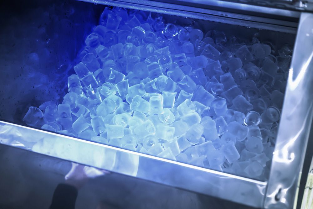A Bunch of Ice Cubes Are Sitting in A Metal Container Under a Blue Light - Townsville Ice Machine in Cairns, QLD