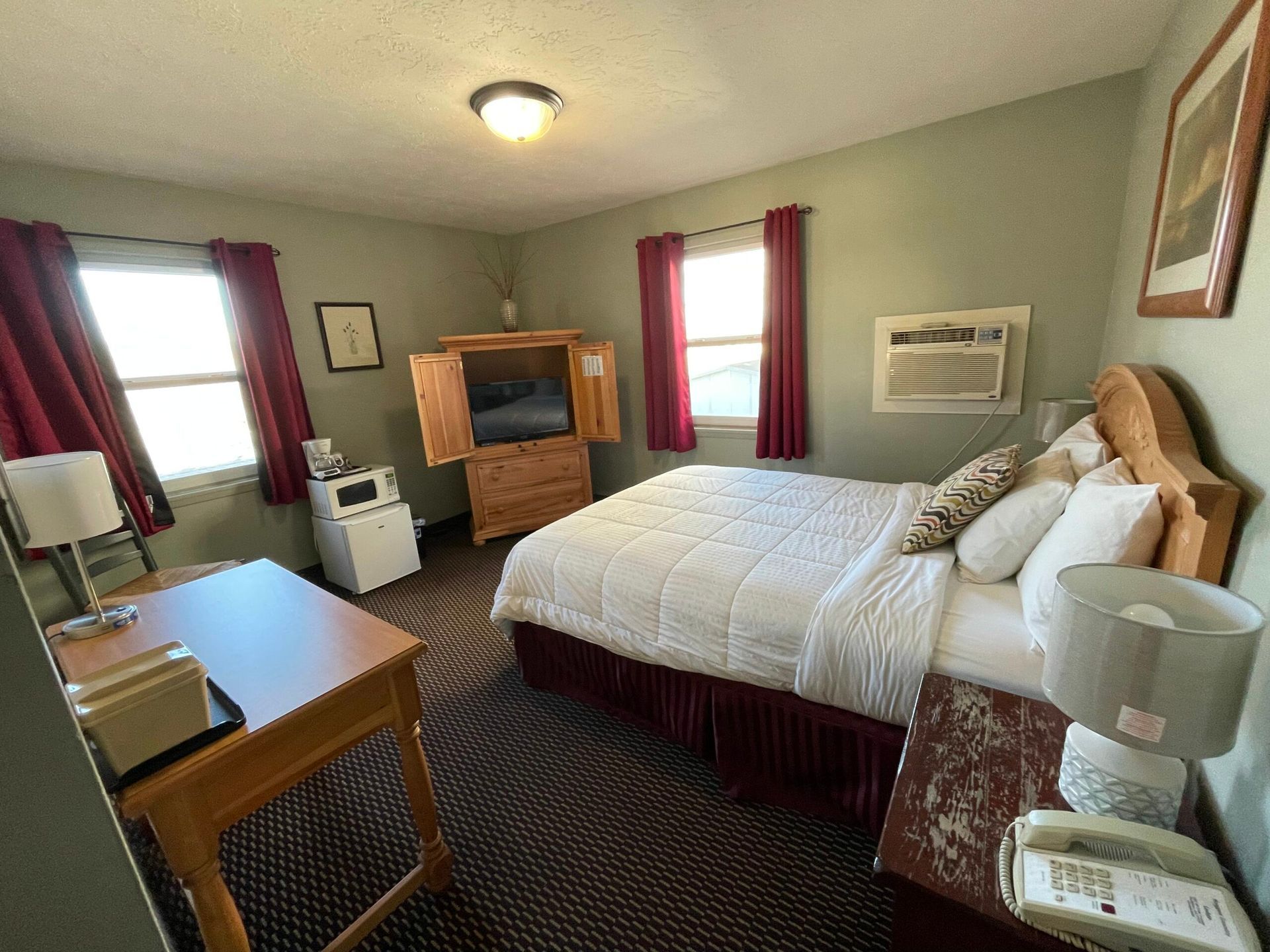 A hotel room with a bed , desk , lamp and television.