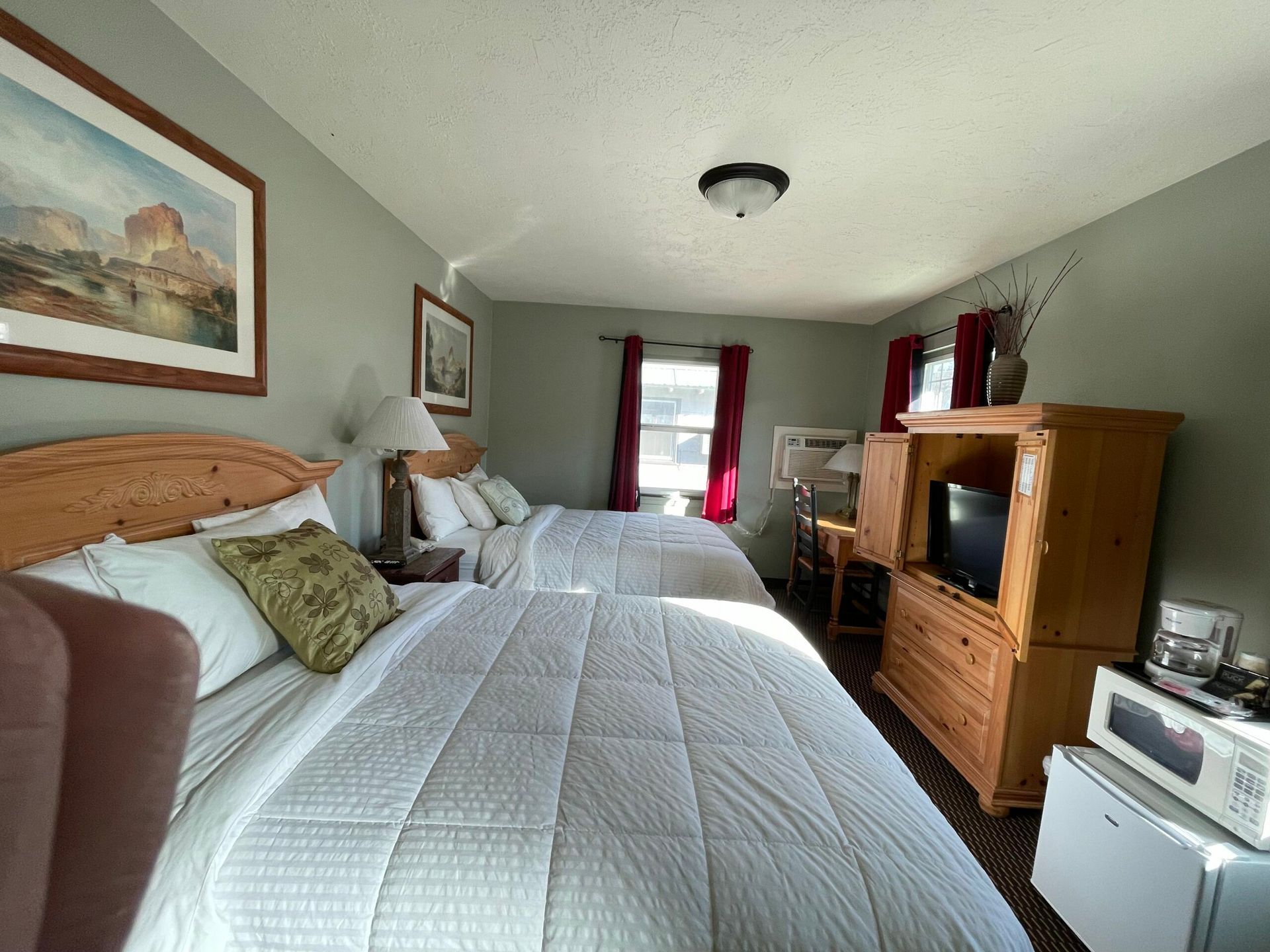 A hotel room with two beds and a television