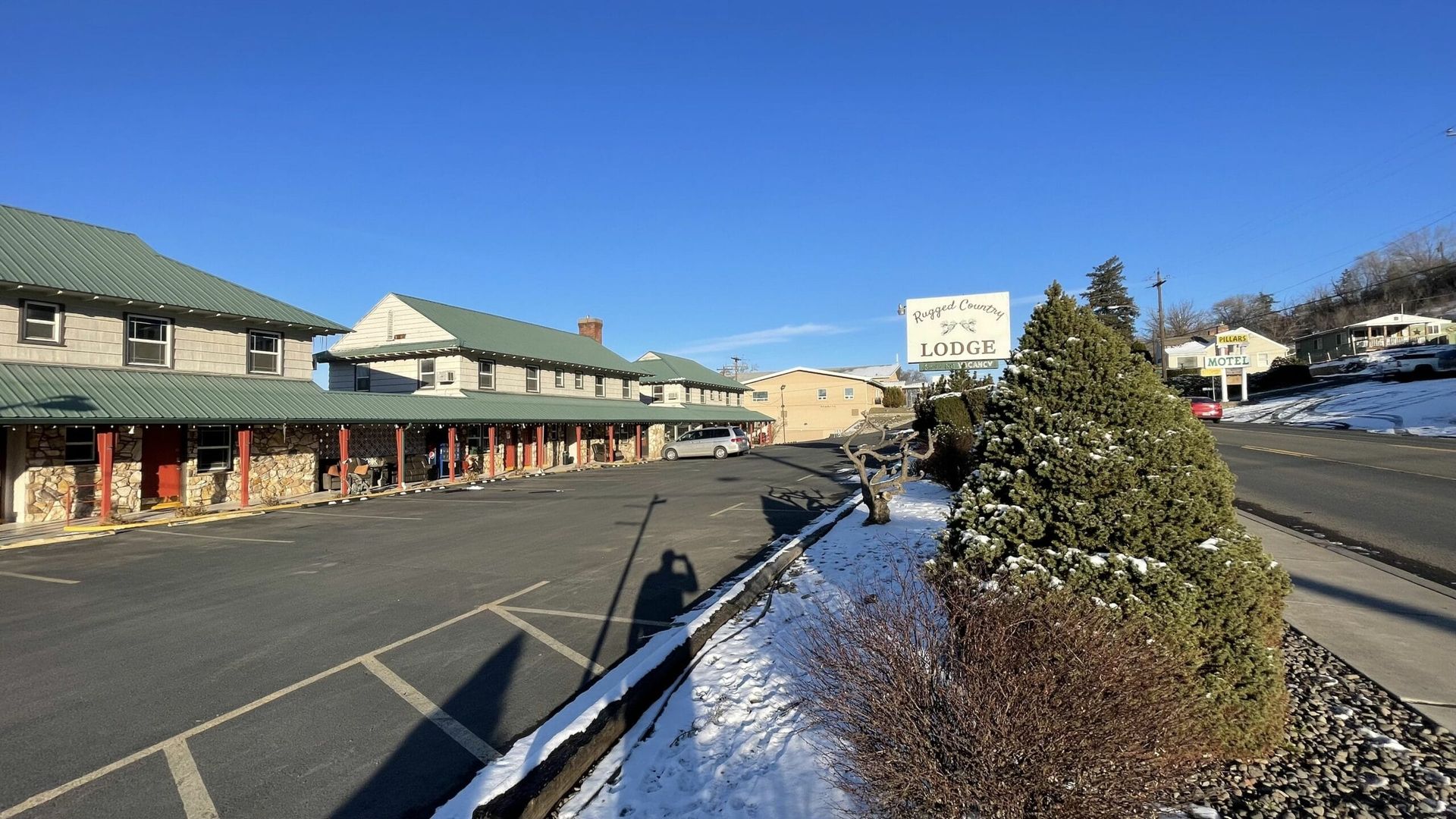 A large building with a green roof is sitting next to a snowy road.