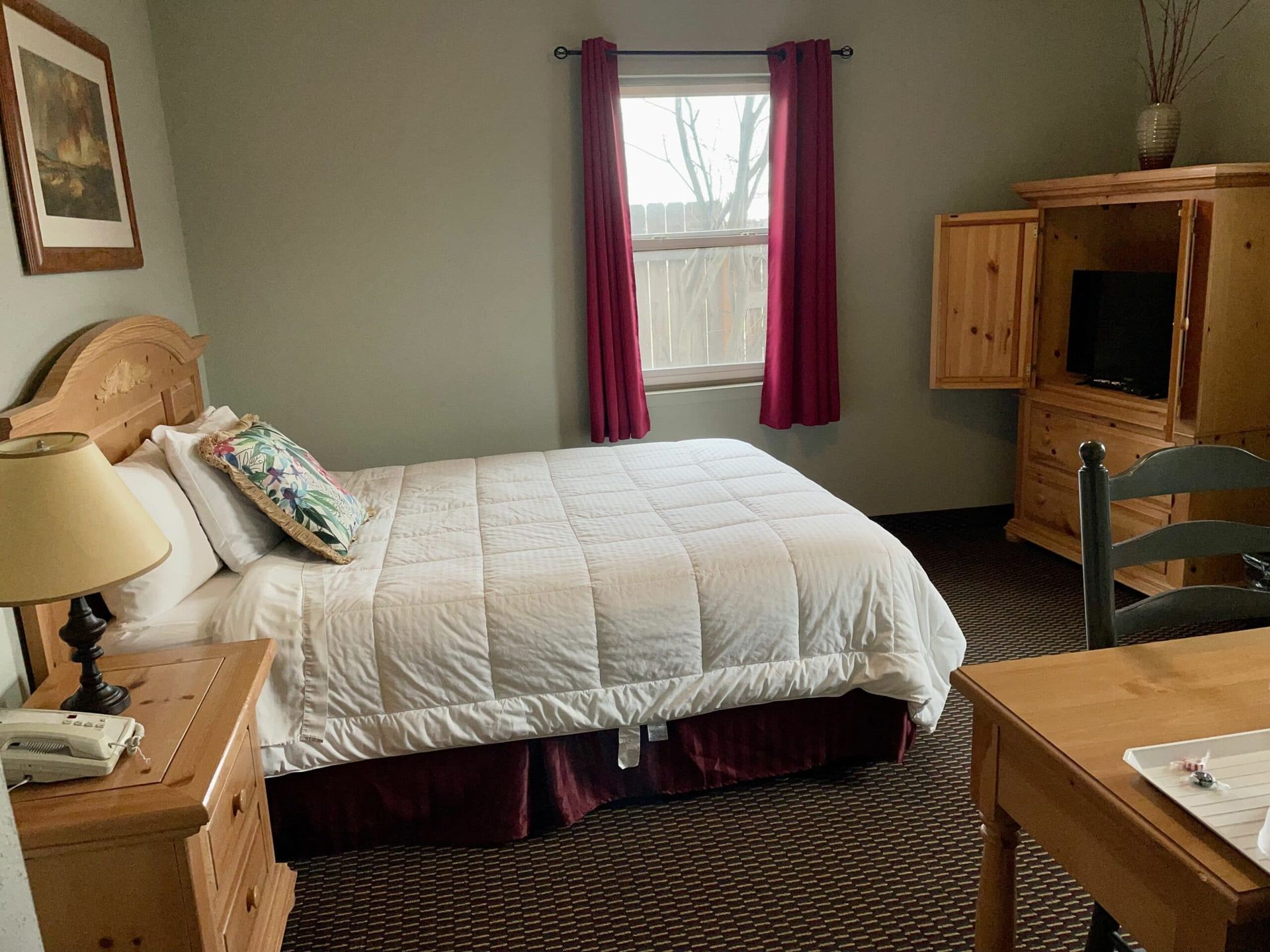 A bedroom with a bed , dresser , desk , chair and television.