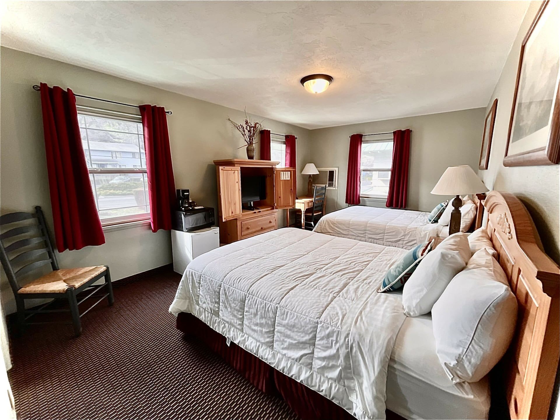 A hotel room with two beds , a chair and a television.