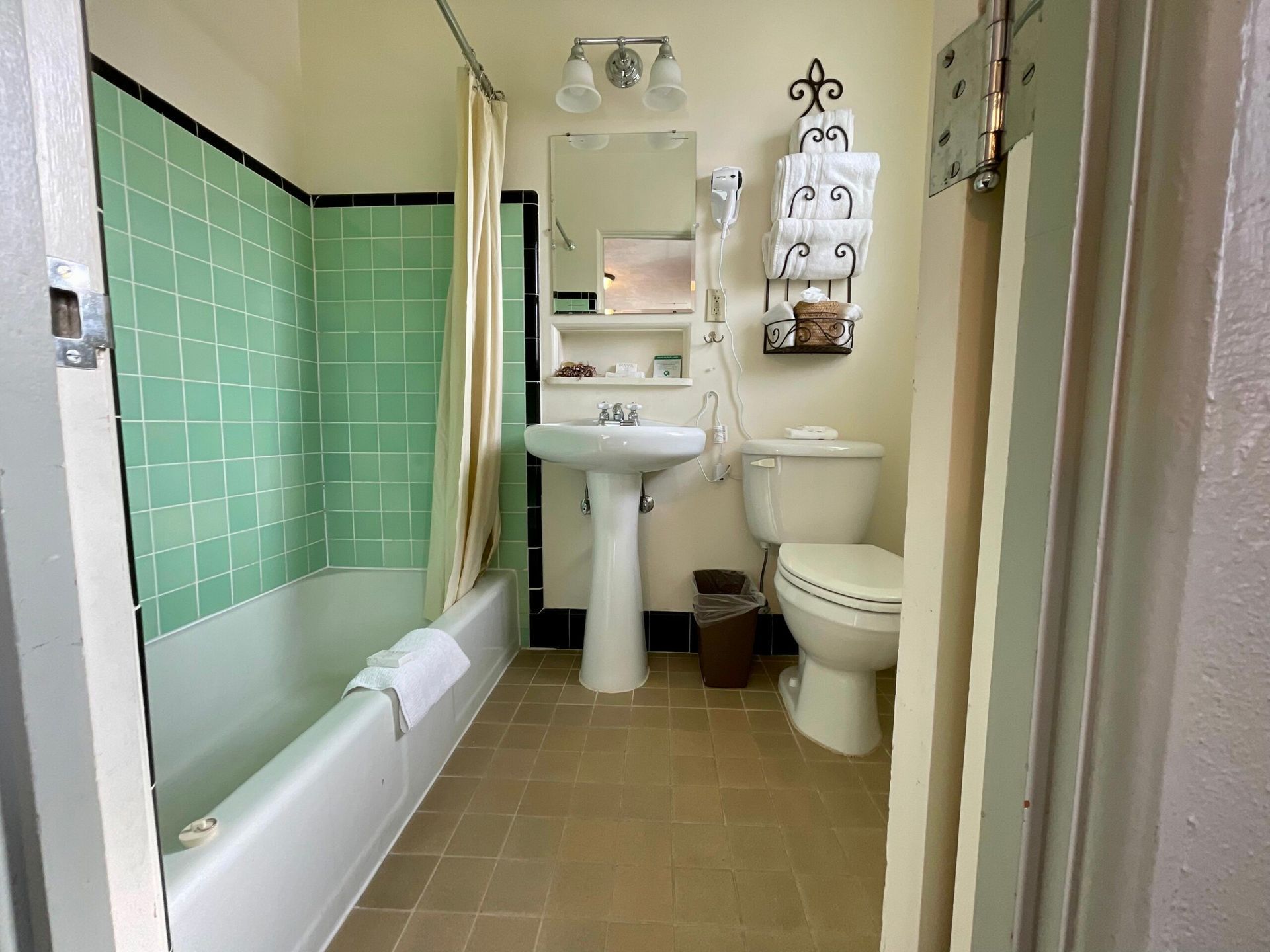 A bathroom with green tiles , a sink , toilet and bathtub.