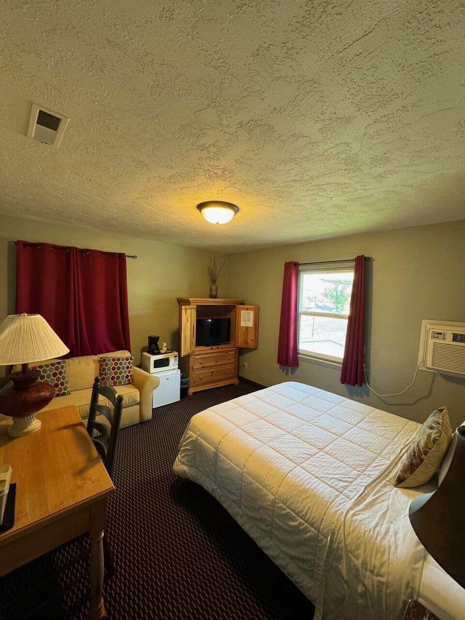 A hotel room with a king size bed and a television