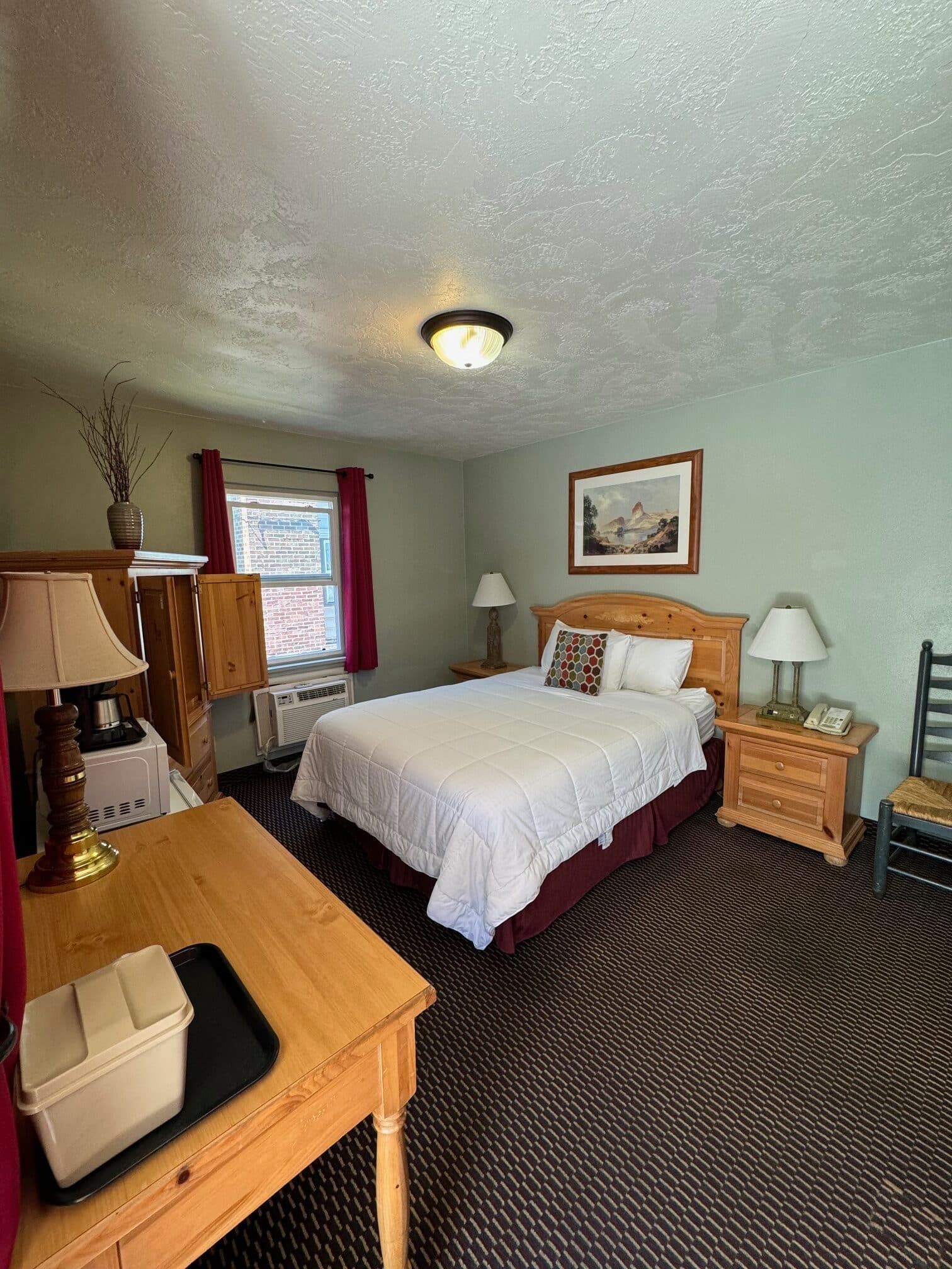 A hotel room with a king size bed and a desk.
