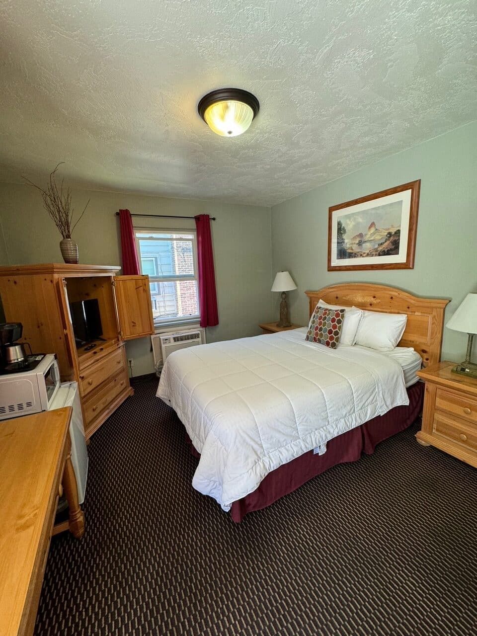 A hotel room with a king size bed and a microwave.