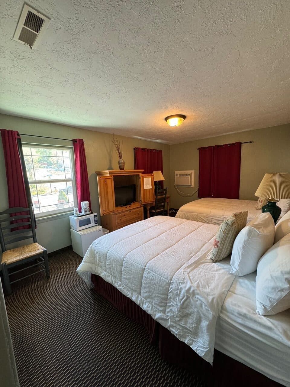 A hotel room with two beds and a television.
