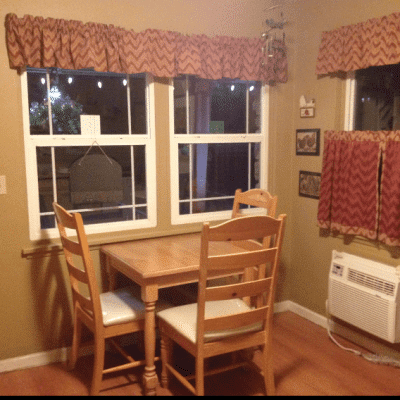 A kitchen with a table and chairs in front of two windows