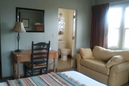 A bedroom with a couch a desk and a mirror