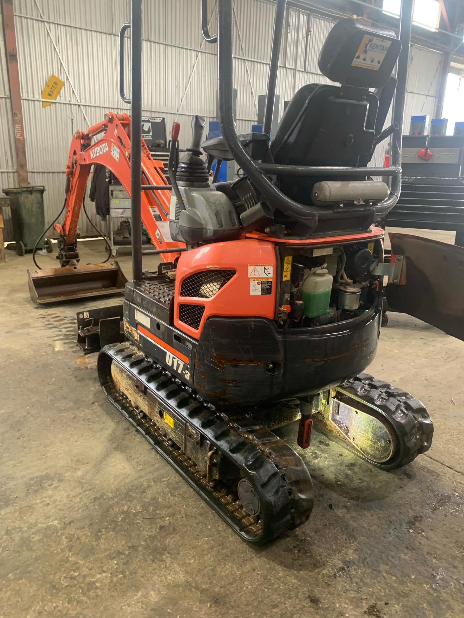 A small orange and black excavator is parked in a garage.— BDM Heavy Vehicle Repairs In Wauchope, NSW