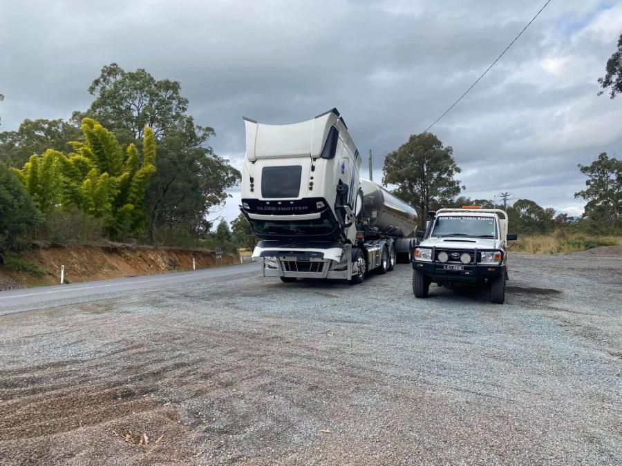 A Truck With Its Hood Up is Parked in a Gravel Lot Next to Another Truck — BDM Heavy Vehicle Repairs In Wauchope, NSW