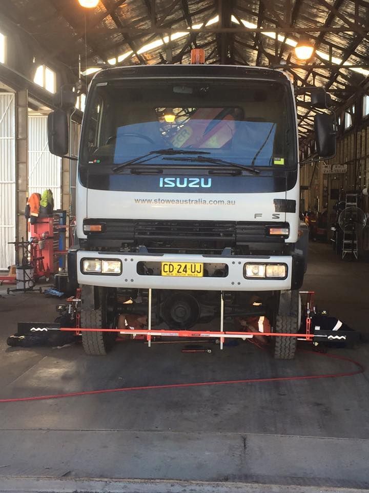 Front view of an Isuzu Truck Undergoing Wheel Alignment Inside A Workshop, With Alignment Equipment In Use — BDM Heavy Vehicle Repairs In Wauchope, NSW
