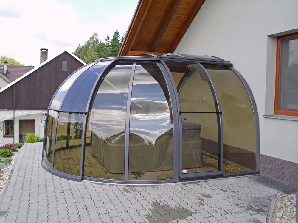 Gebogene Glasterrasse neben einem Haus an einer gepflasterten Auffahrt