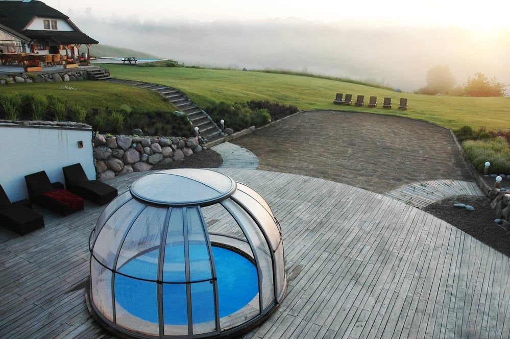 Luxuriöse Terrasse mit rundem, blauem Whirlpool, Sitzgelegenheiten im Patio und Blick auf einen nebelverhangenen Hang