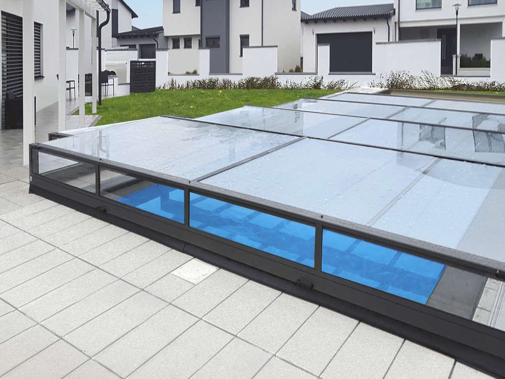 Moderner Innenhof mit niedrigem Glasdach und blauen Paneelen neben weißen Gebäuden