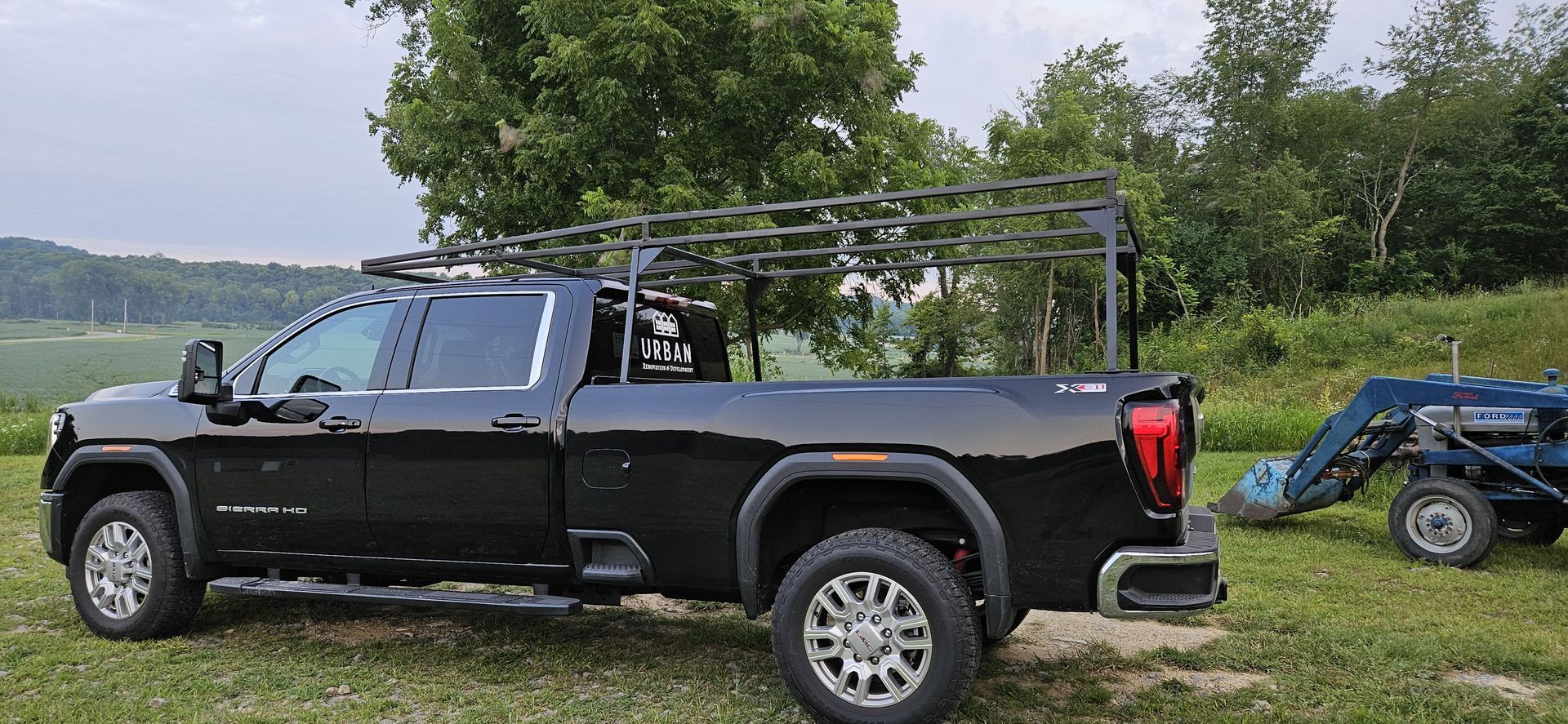 A black truck is parked in a grassy field next to a tractor.