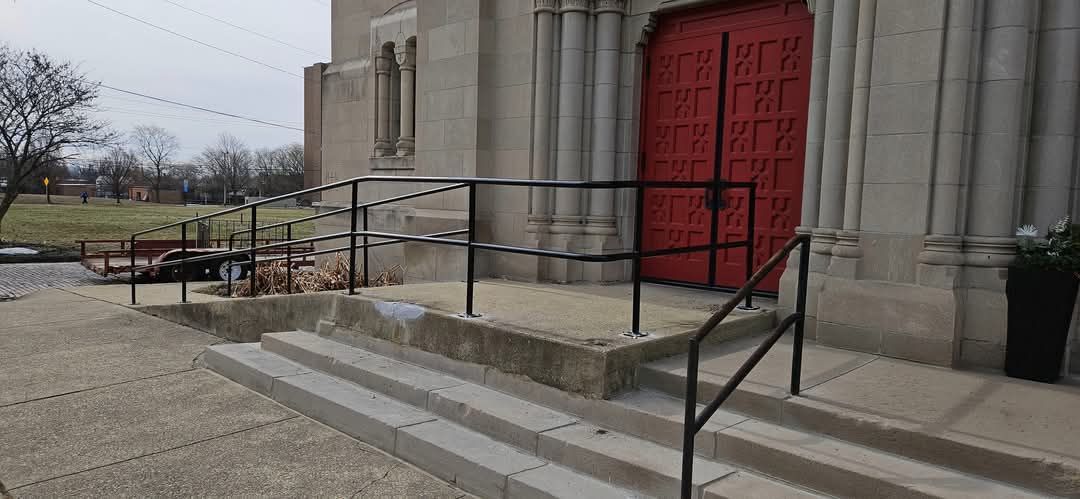 A church with a red door and stairs with a railing.