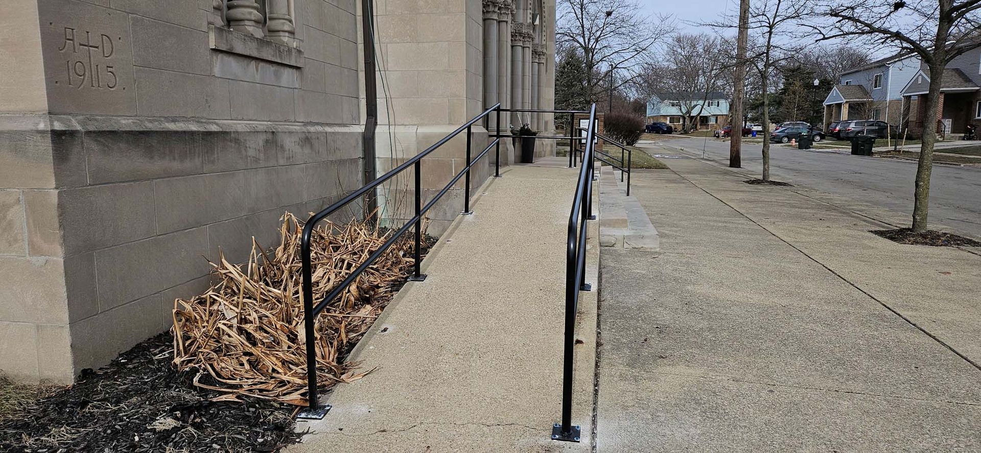 A sidewalk with a railing along the side of a building.