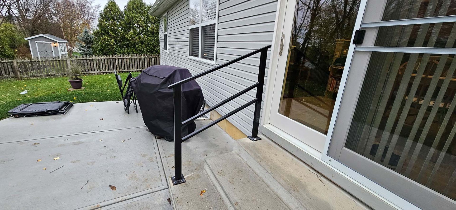 A black railing is sitting on the side of a house next to a sliding glass door.