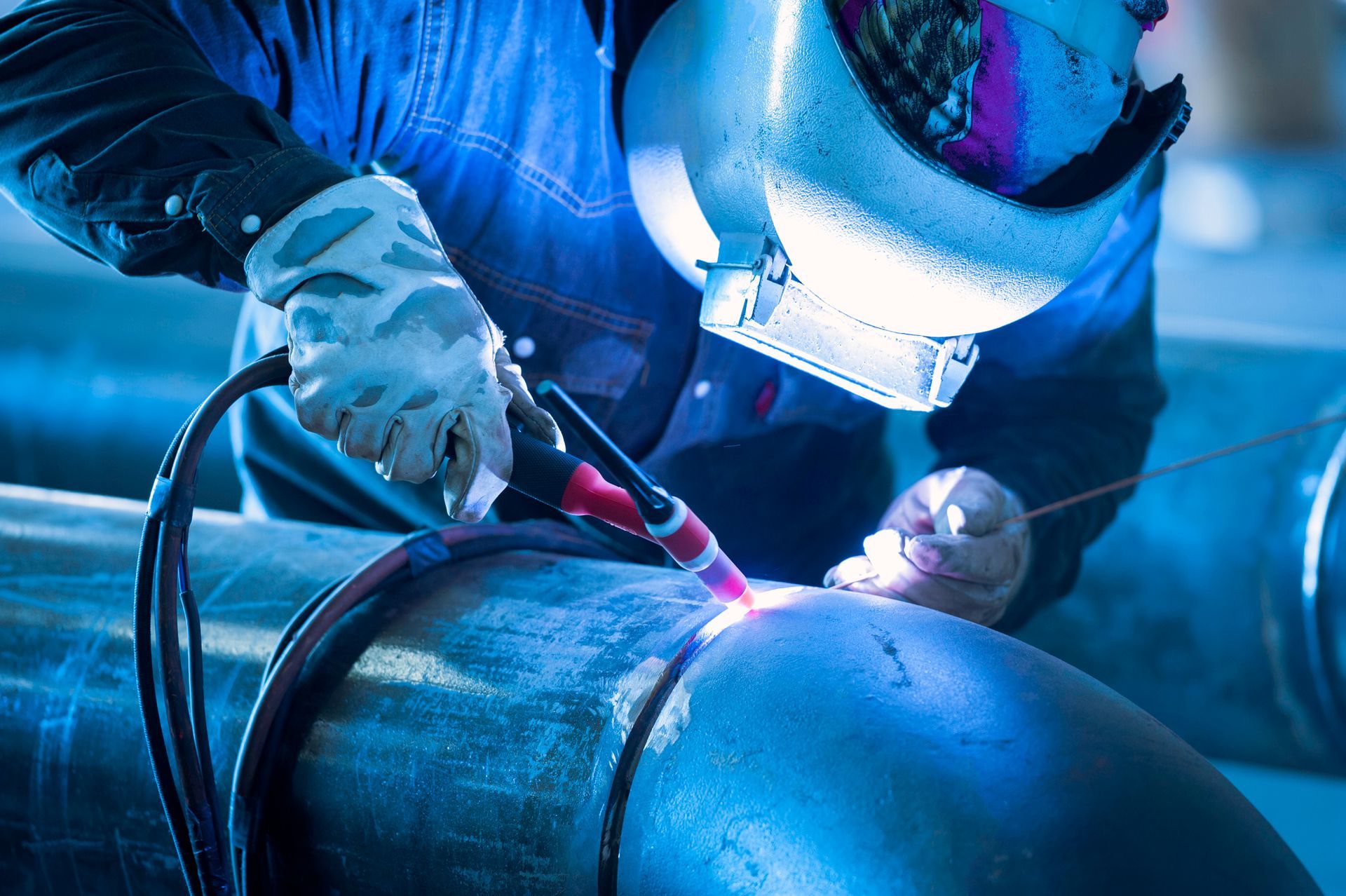A man is welding a pipe with a welding machine.