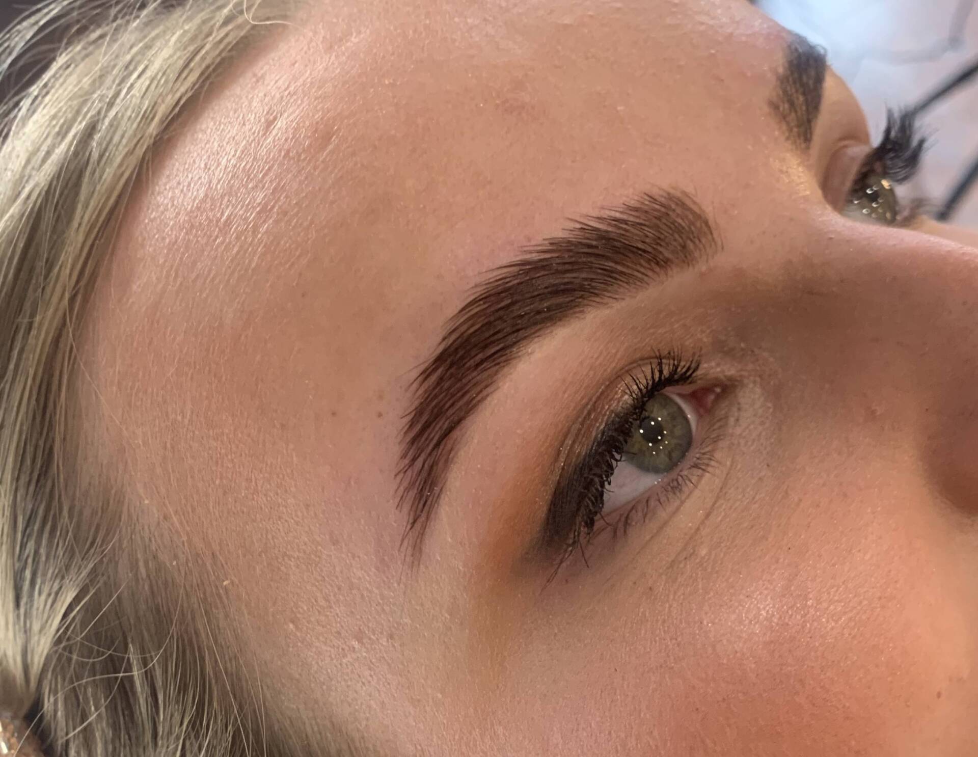 Close-up of a person's face with freshly styled, dark brown eyebrows and light skin.