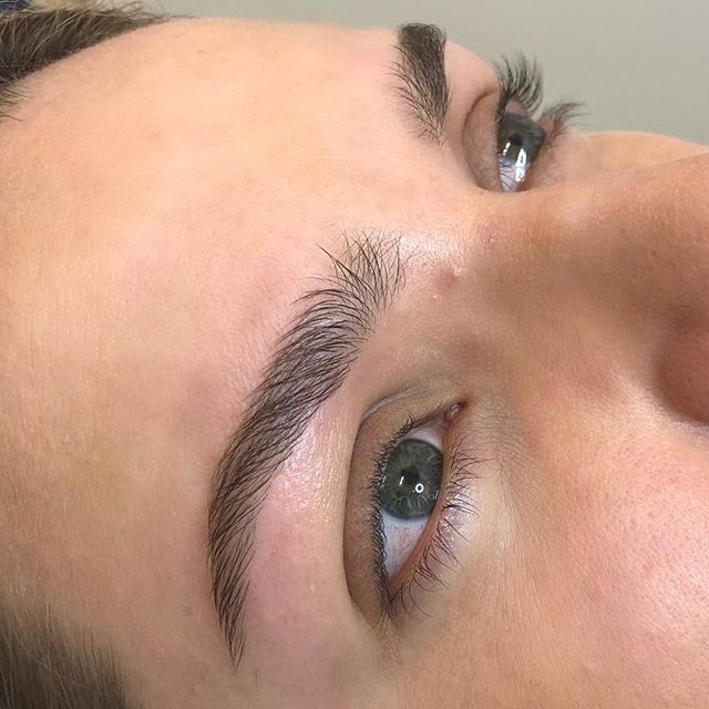 Close-up of a person's face, showing a groomed eyebrow and eye with blue-grey iris.
