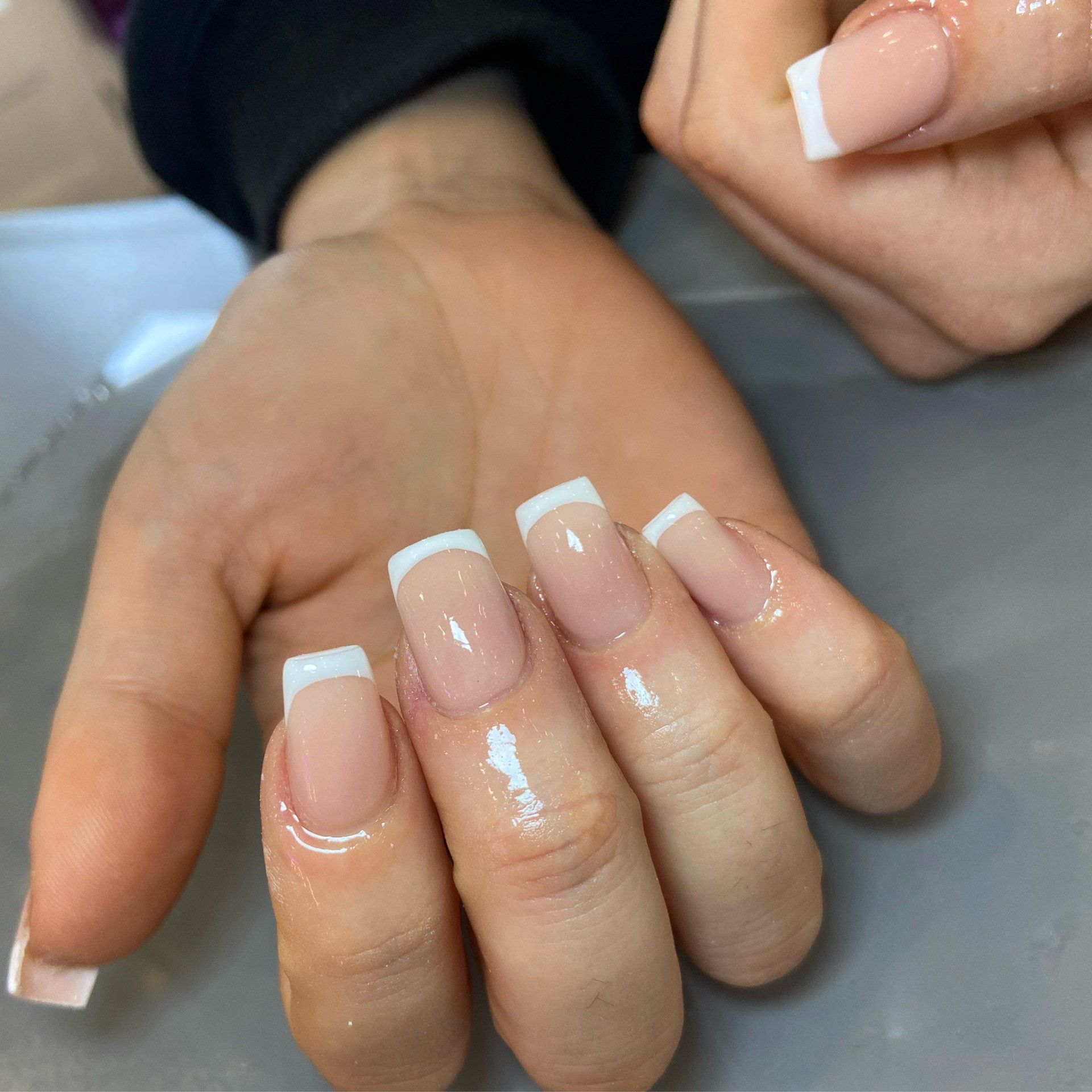 Well-manicured hand with French tip acrylic nails.