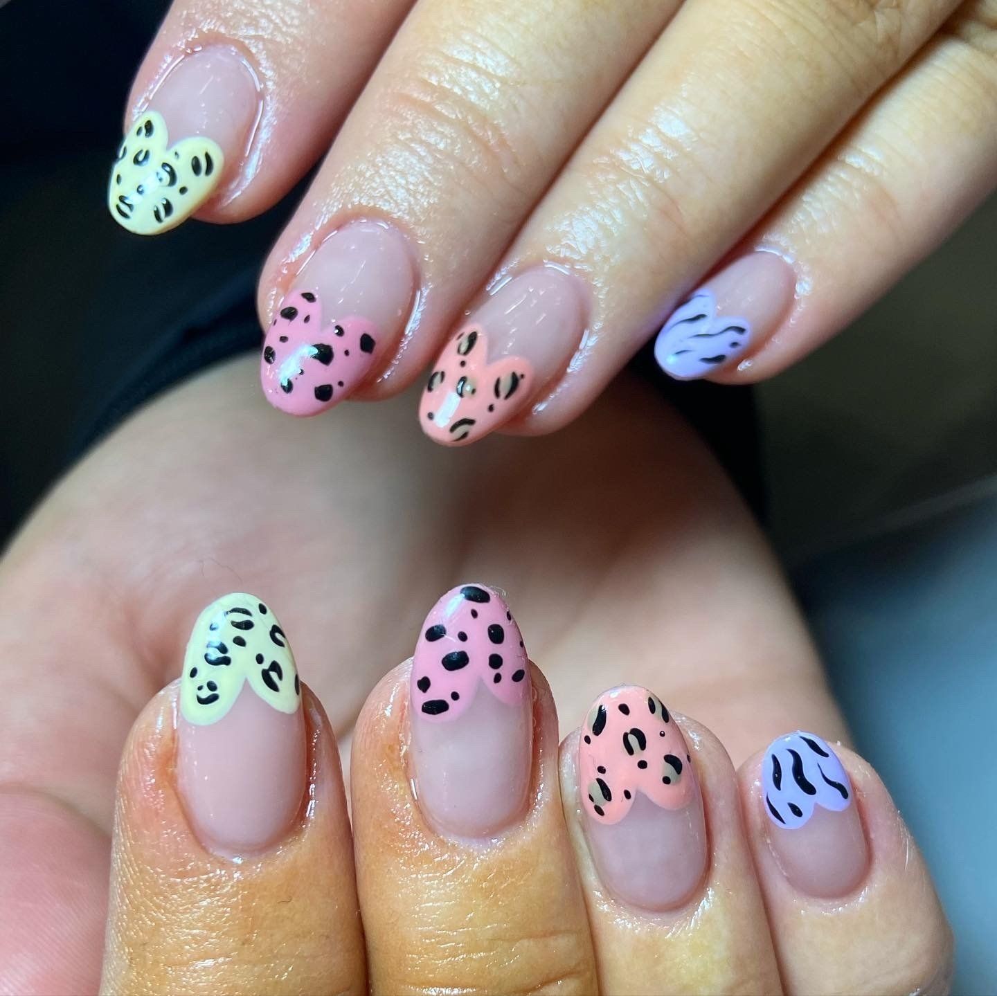 Close-up of painted nails with a French tip design featuring colorful animal print patterns.