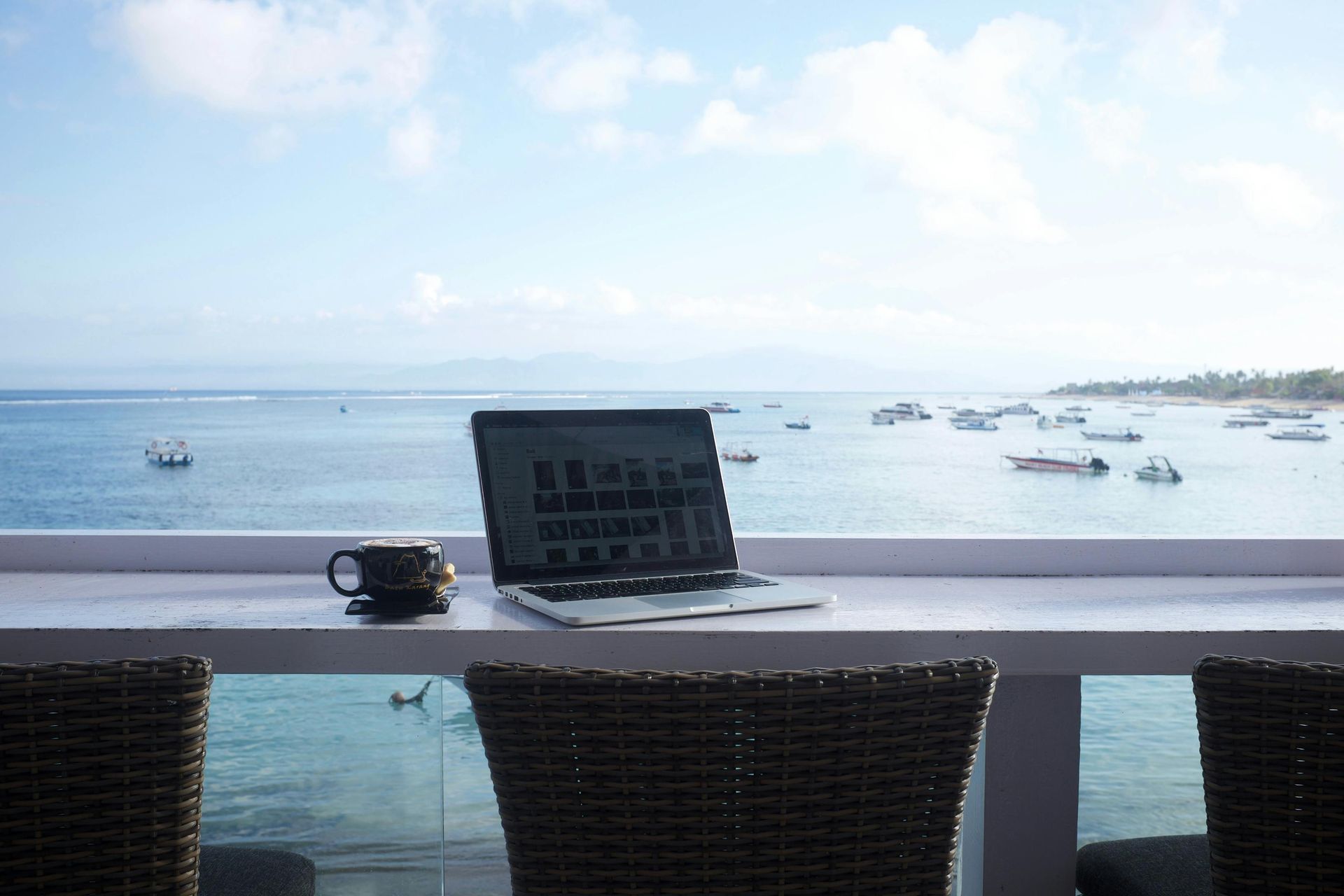 A man is sitting at a table with a laptop and shaking hands with a man.