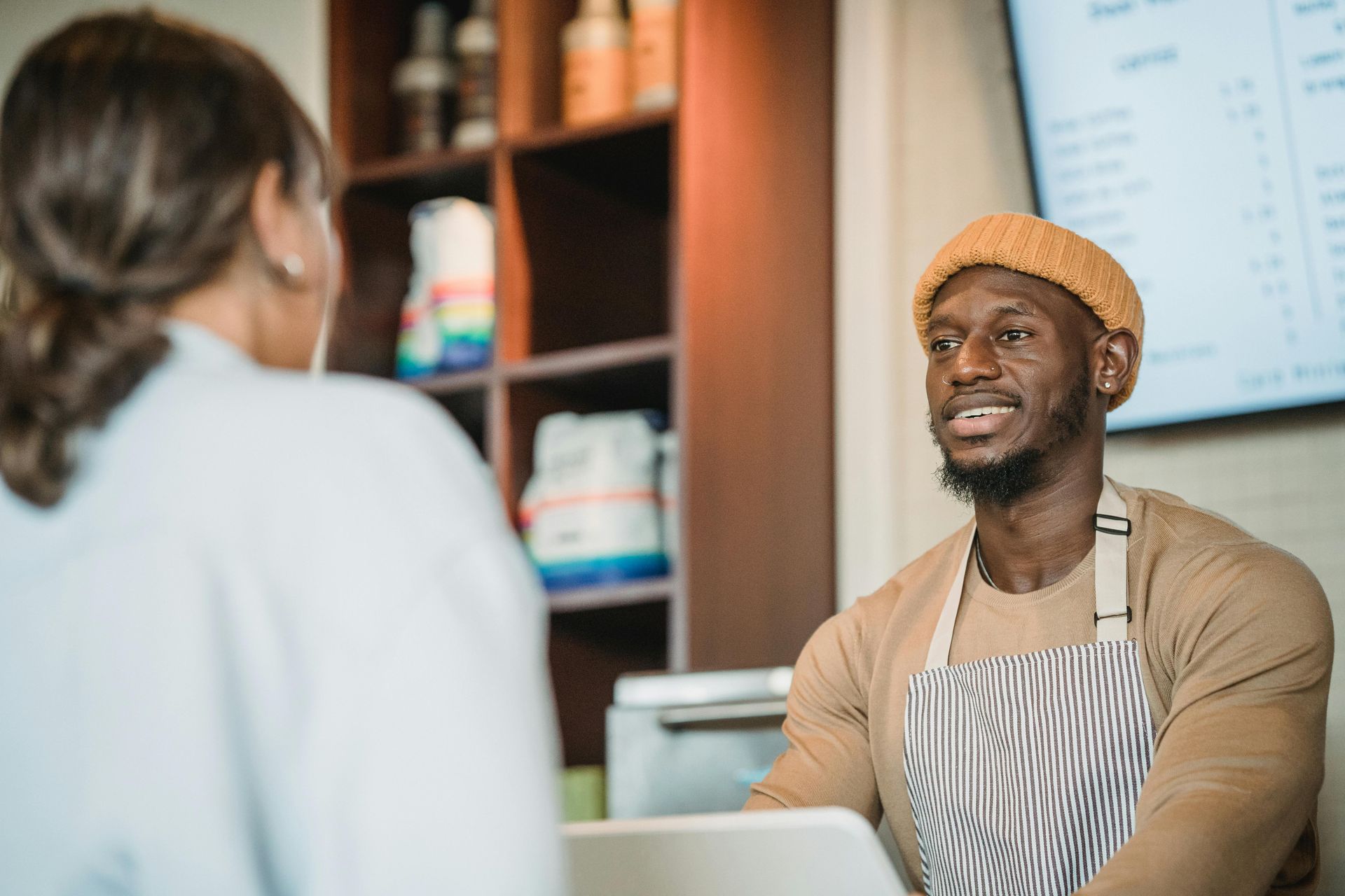 A man is sitting at a table with a laptop and shaking hands with a man.