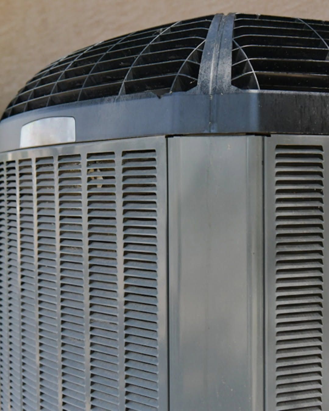 Close-up of a gray HVAC unit with louvered vents and a black curved top on a rooftop.