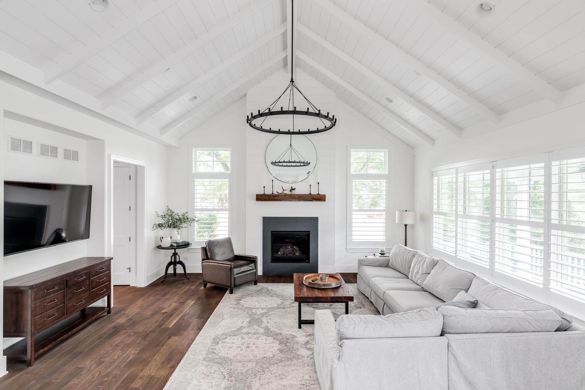 Modern farmhouse living room with farmhouse-themed furniture and white blinds.