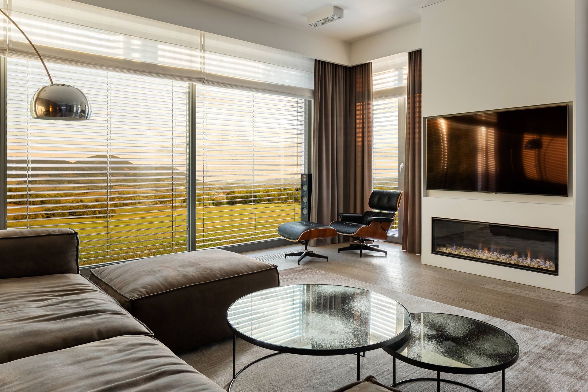 A cozy living room with sunset light streaming in through windows with blinds and drapery at Window