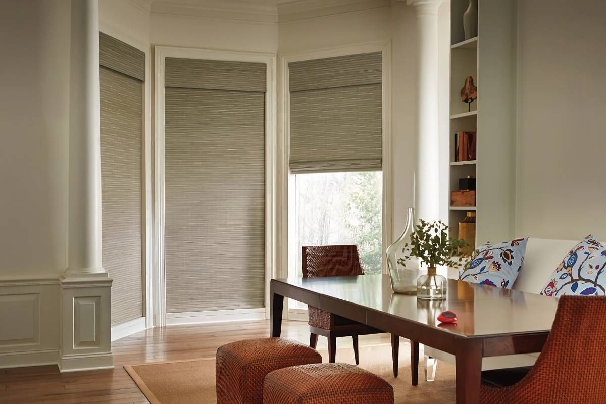 Two closed and one partially opened Hunter Douglas Provenance® Woven Wood Shades on dining room windows near Houston, TX
